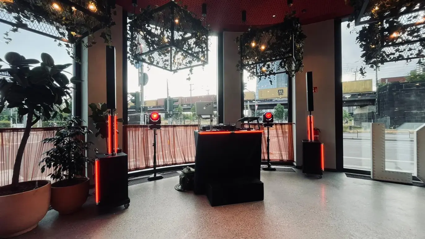 DJ-Pult mit zwei Säulenlautsprechern und Moving-Heads am Fenster als PA-Anlage für Karneval mieten.