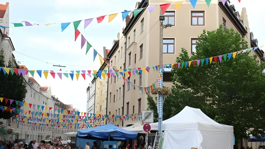 Bunte Wimpelketten über der Straße mit Pavillonzelten und Gästen als Veranstaltungstechnik für Straßenfest mieten.