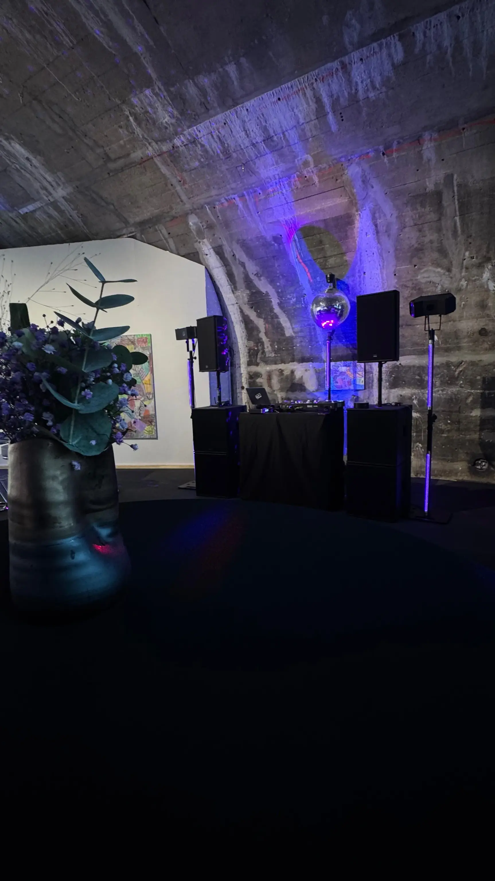 DJ-Aufbau mit Diskokugel, Lautsprechern und blauen Uplights in einem Betongewölbe als PA-Anlage für Firmenevent mieten.