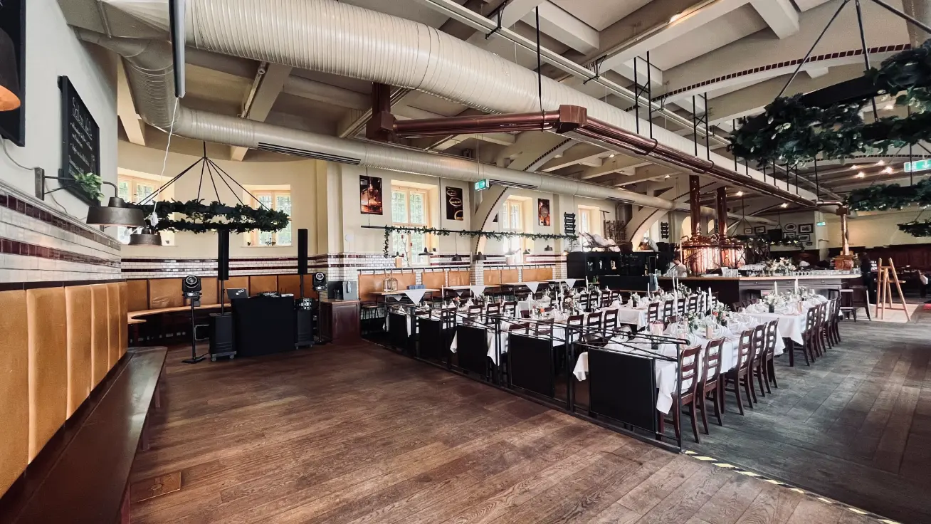 Langer festlich gedeckter Tisch in einer Halle mit Säulenlautsprechern seitlich, Veranstaltungstechnik für Hochzeit mieten.