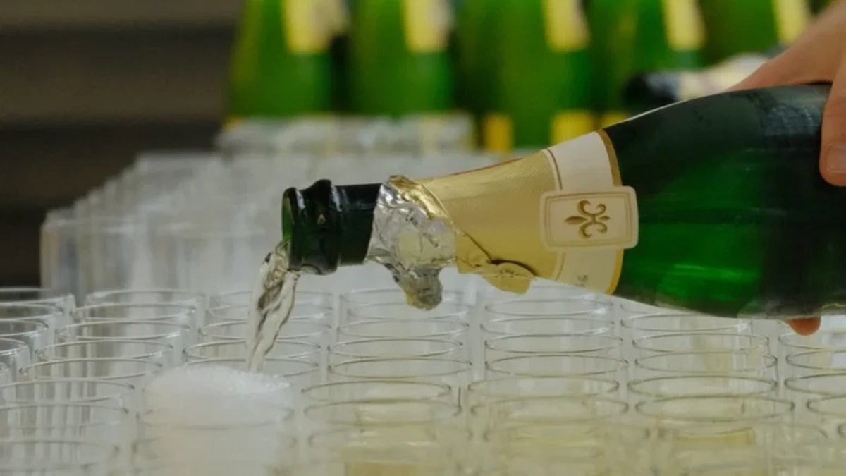 Sekt wird bei einer Vereinsfeier in aufgereihte Gläser eingeschenkt