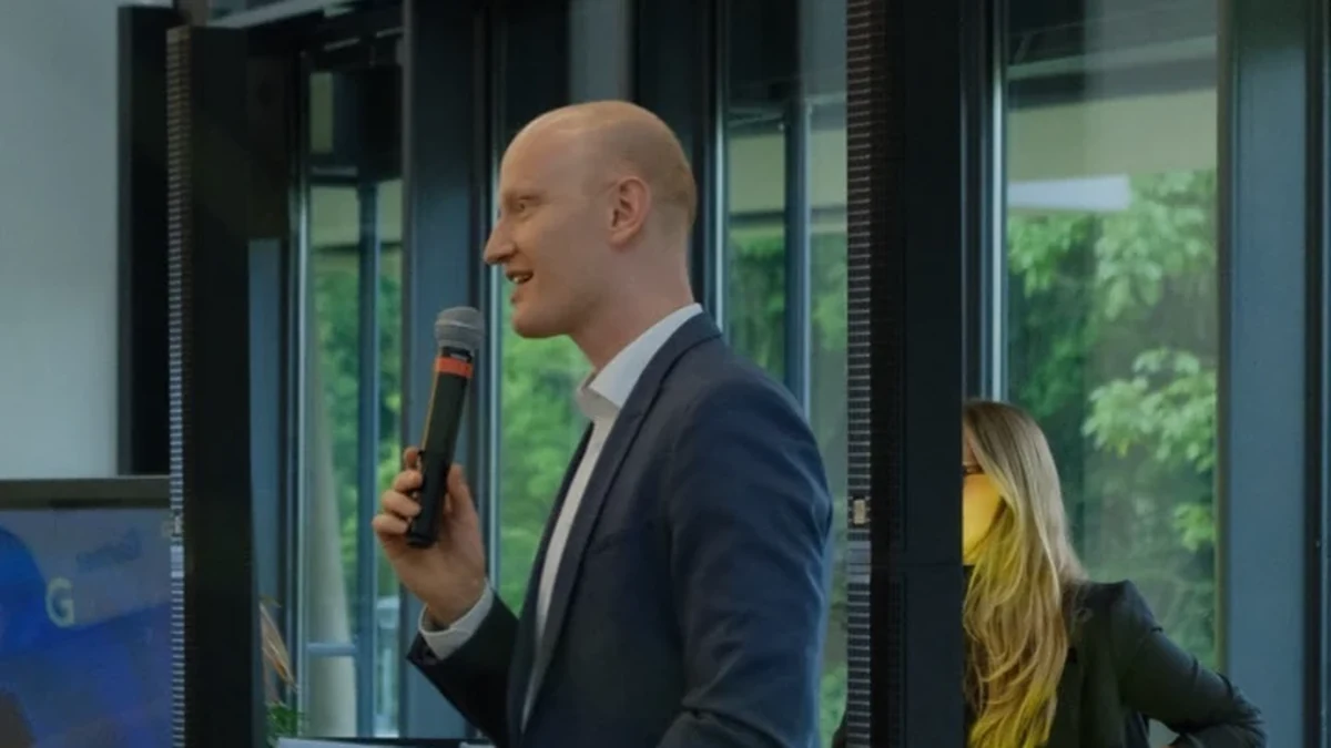Redner mit Mikrofon und Notizkarten hält eine Abirede vor Publikum