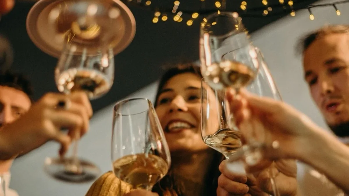 Gäste stoßen unter warmweißen Lichtern mit Sekt und Wein auf einen runden Geburtstag an
