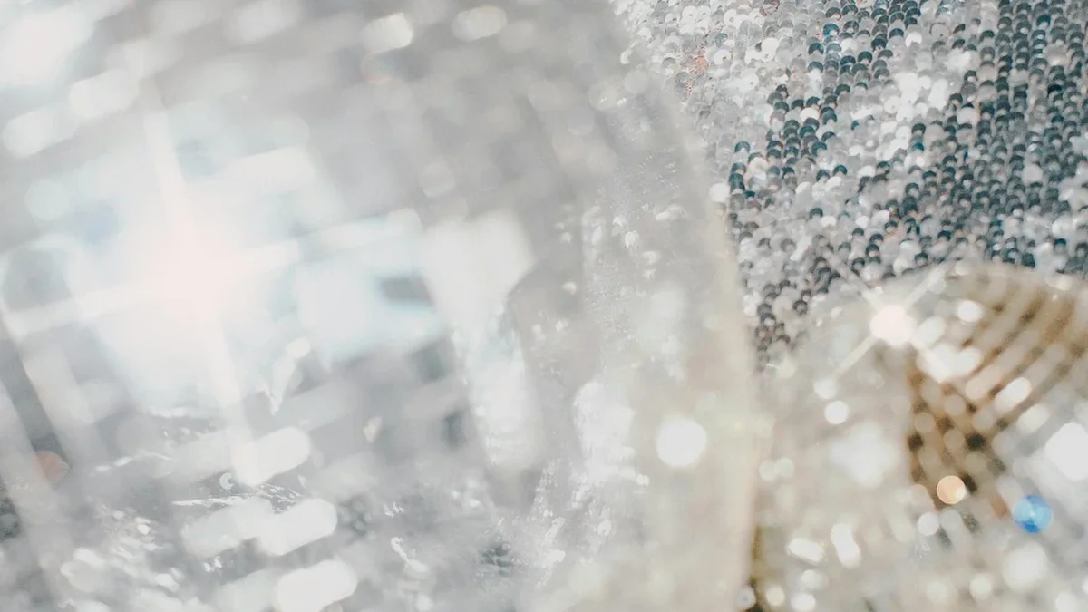 Glitzernde Discokugeln neben silbernem Paillettenstoff als Deko für eine Mottoparty