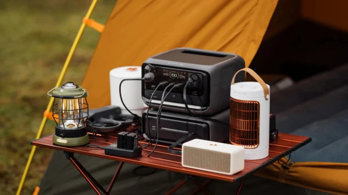 Powerstation mit angeschlossenen Geraeten und Campinglampen auf einem Tisch vor einem Zelt