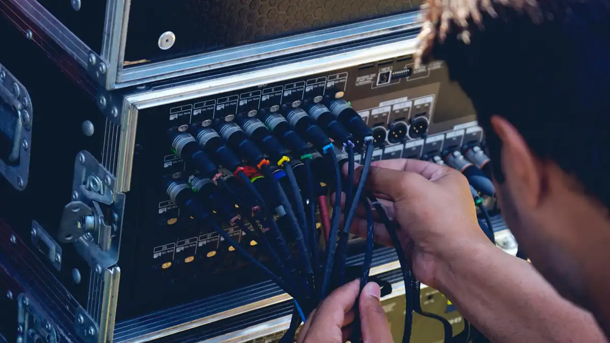 Techniker sortiert Kabel an der Anschlussleiste eines Technikracks im Transportcase