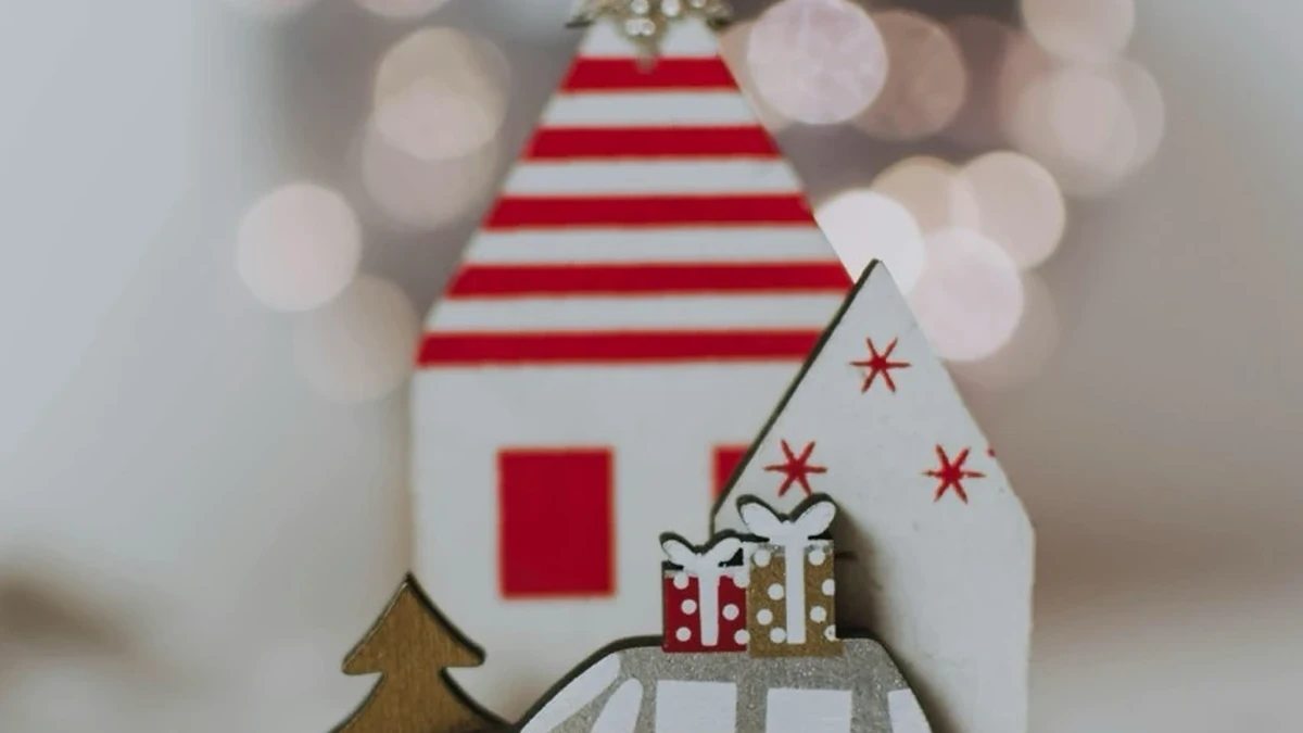 Weihnachtliche Miniaturdeko aus Holz mit Häusern und Tannenbaum auf einer Holzscheibe