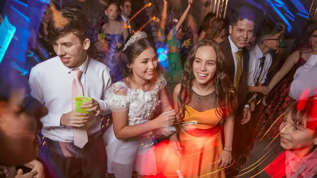 Jugendliche tanzen bei einem festlichen Ball in buntem Partylicht