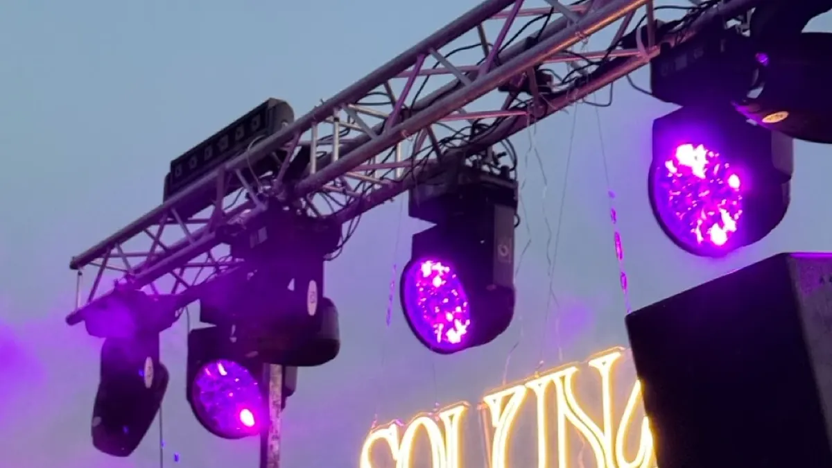 Open-Air-Bühne mit Lichttraverse, violetten Lichteffekten und Nebel, davor das Publikum
