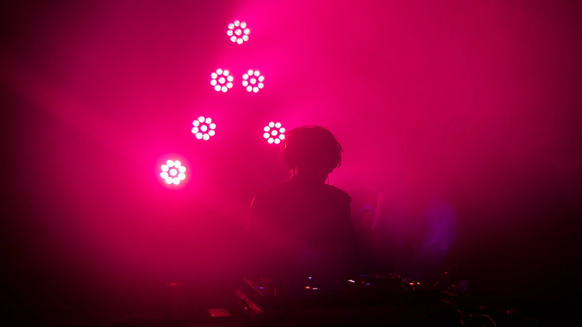 Silhouette eines DJs vor pinkem Scheinwerferlicht und dichtem Nebel bei einer Nachtveranstaltung