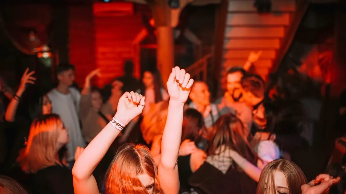 Tanzende Menschen mit erhobenen Armen auf einer Party in rotem Licht