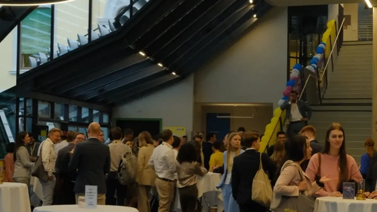 Gäste bei einem Empfang in einem Foyer mit weiß gedeckten Stehtischen und Luftballons