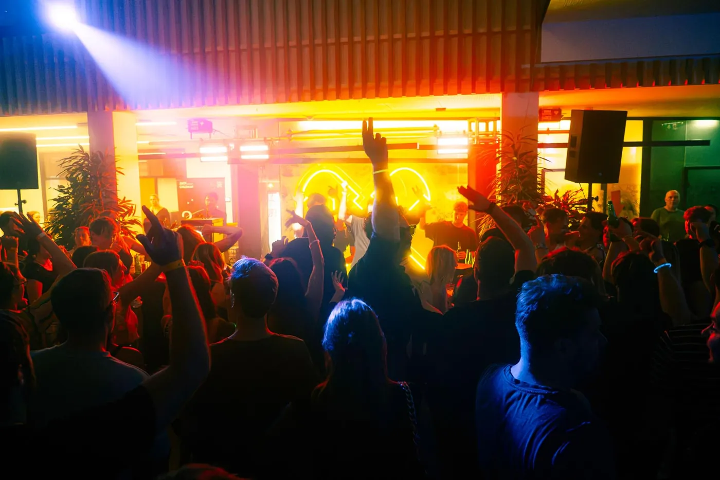 Publikum mit erhobenen Händen beim Rave Eisen in der Grazer Bankfiliale, farbige Lichttechnik und Nebel