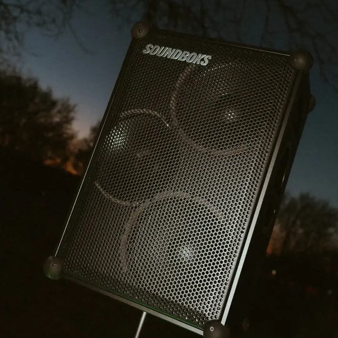 Akku-Lautsprecher einer Musikanlage bei einer Party im Garten in der Dämmerung