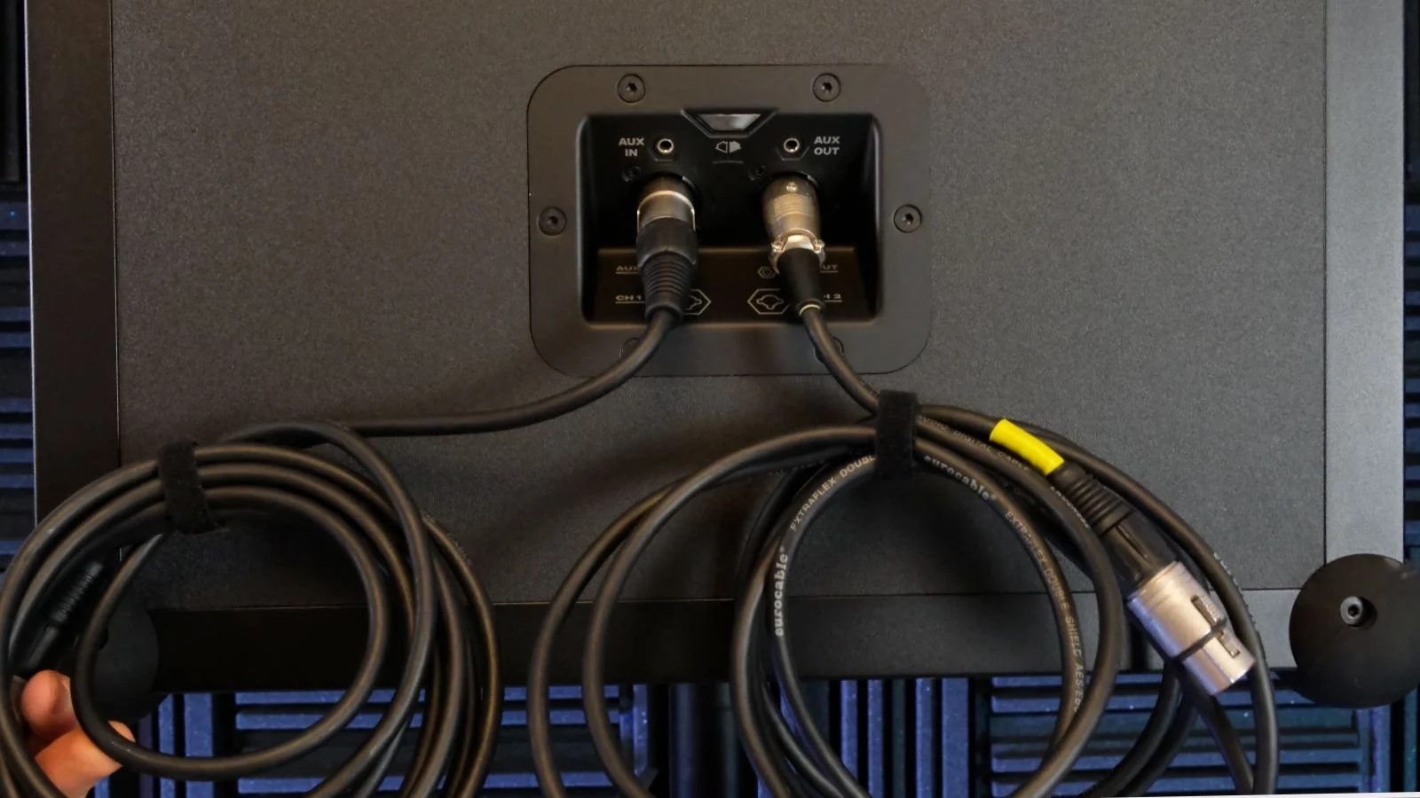 Anschlussfeld eines Soundboks Lautsprechers mit AUX-Eingang und aufgerollten XLR-Kabeln in Nahaufnahme.