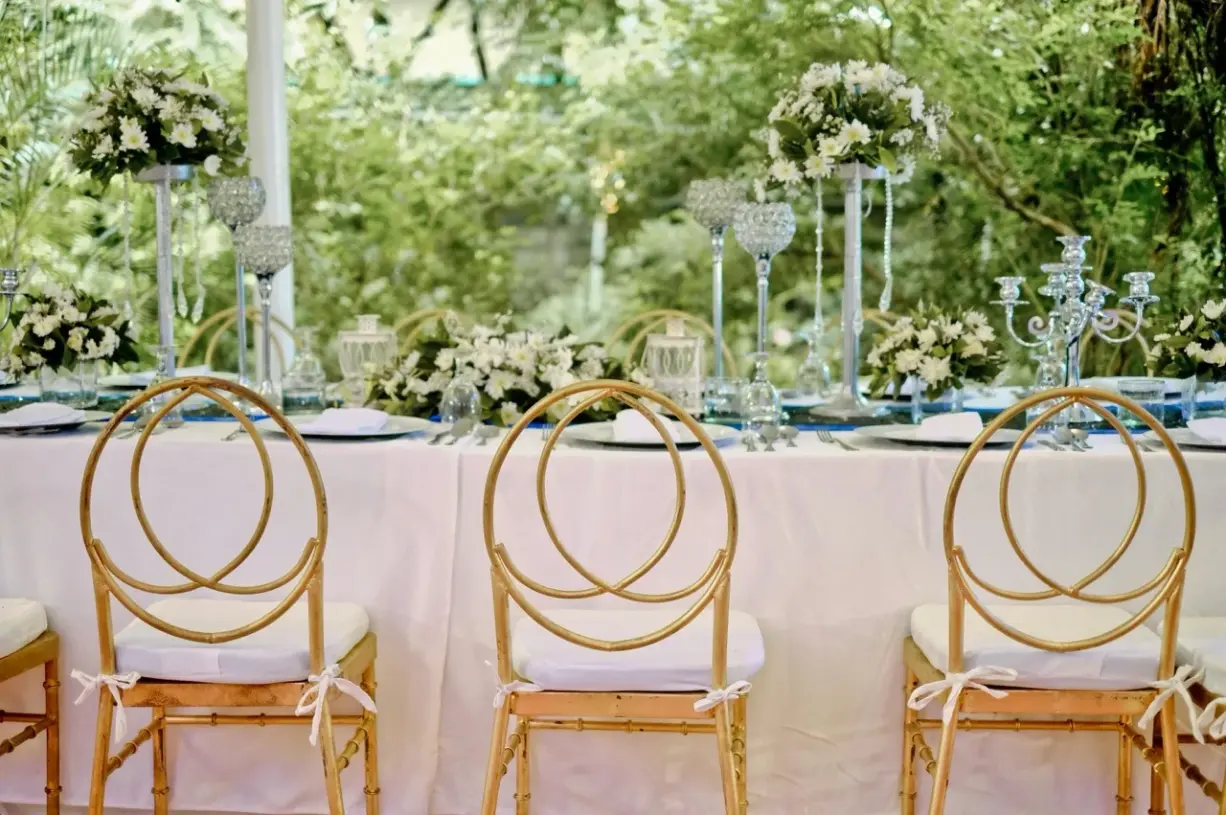 Elegant gedeckter Gartentisch für eine Hochzeit mit schlichter Blumendeko und hellen Stühlen