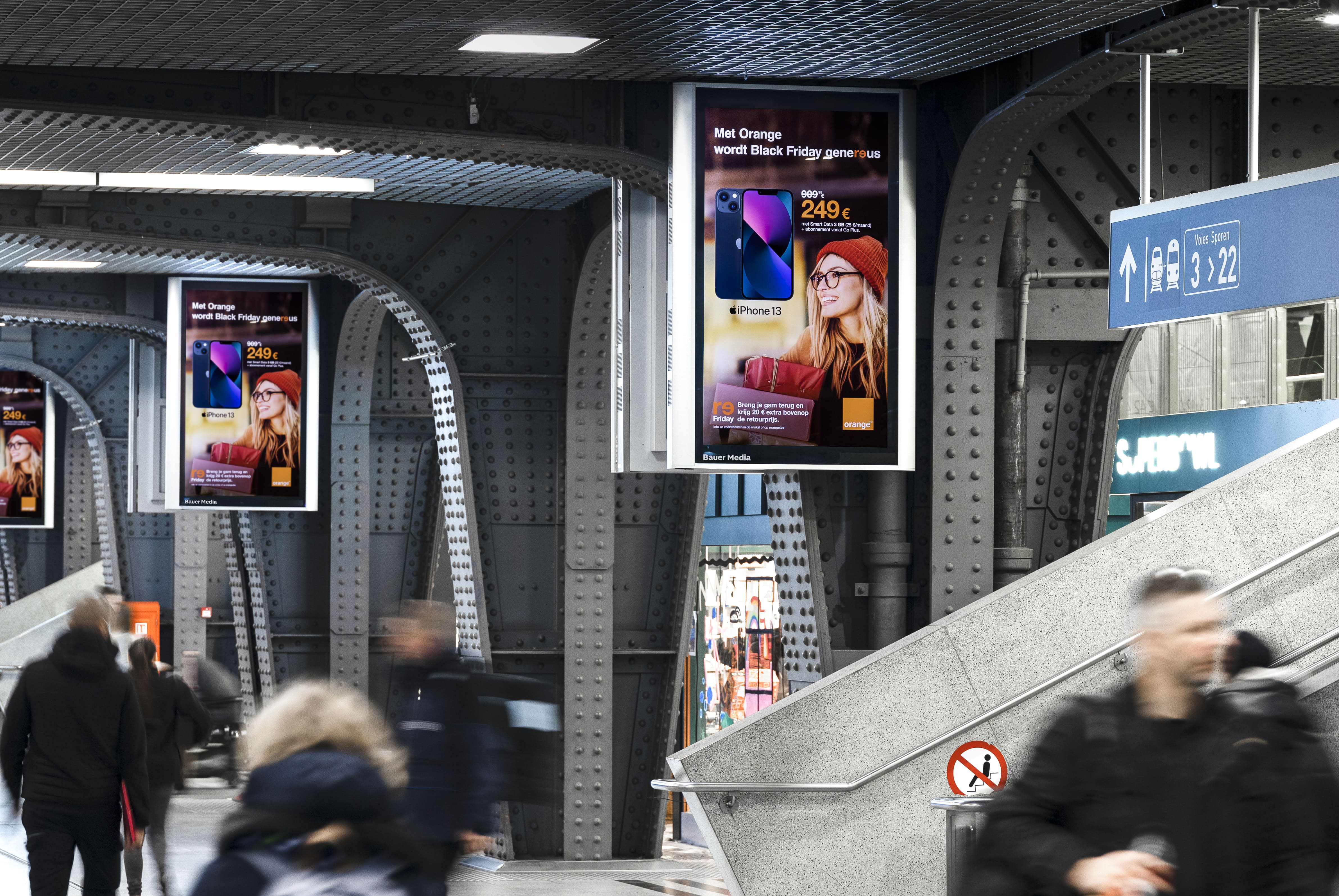 Digital advertisement on the station platform with commuters waiting for their train