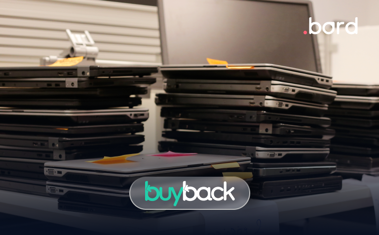 Stacks of used laptops with sticky notes on a table. buyback and .bord logos