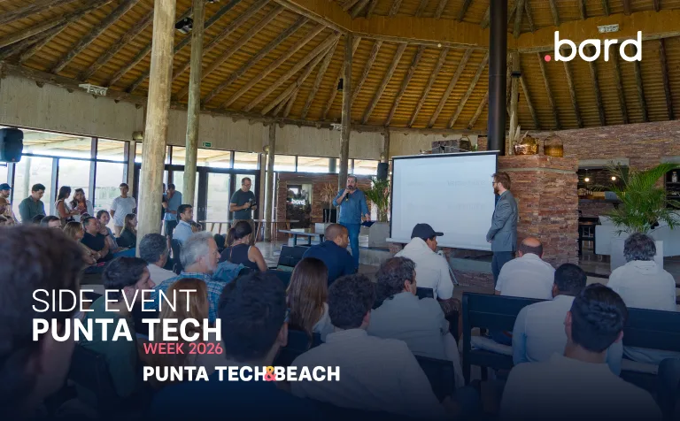 Audience listens to a speaker beside a screen under a wooden roof; text: Side Event Punta Tech Week 2026