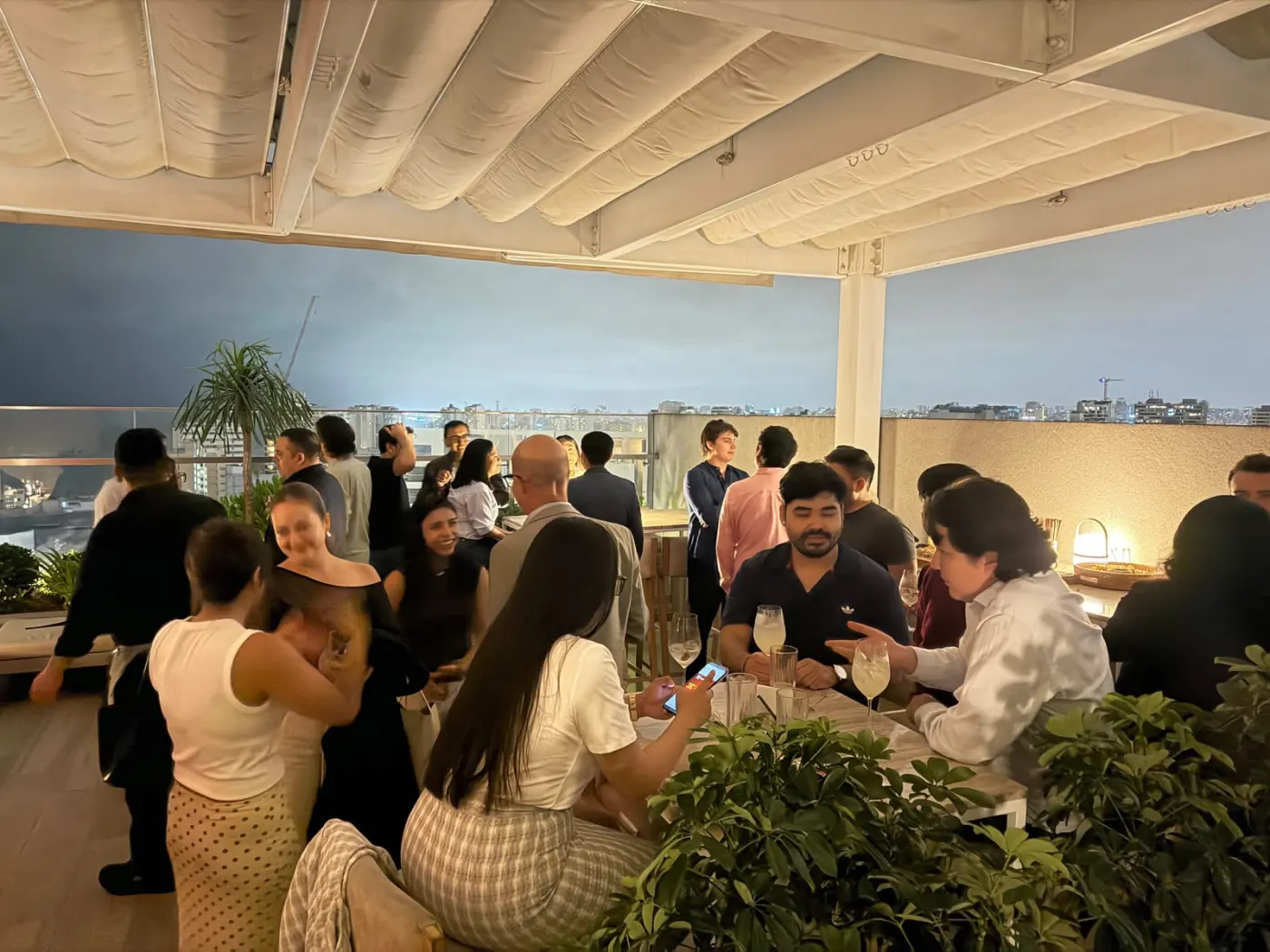 Guests chat over drinks on the 27 Tapas terrace in Miraflores, with Lima at night in the background
