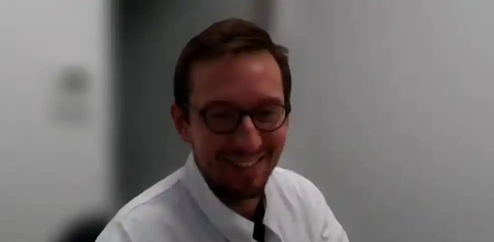 Portrait d'un médecin souriant lors d'une conférence vidéo sur la télésurveillance et les CAR-T en hématologie