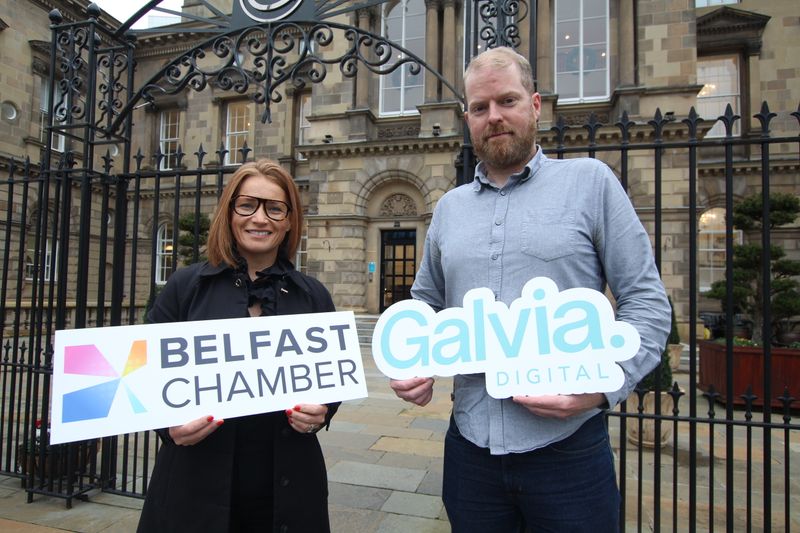 Lisa Comerton on the left and Martin Naughton outside Custom House in Belfast, holding logo cut-outs.
