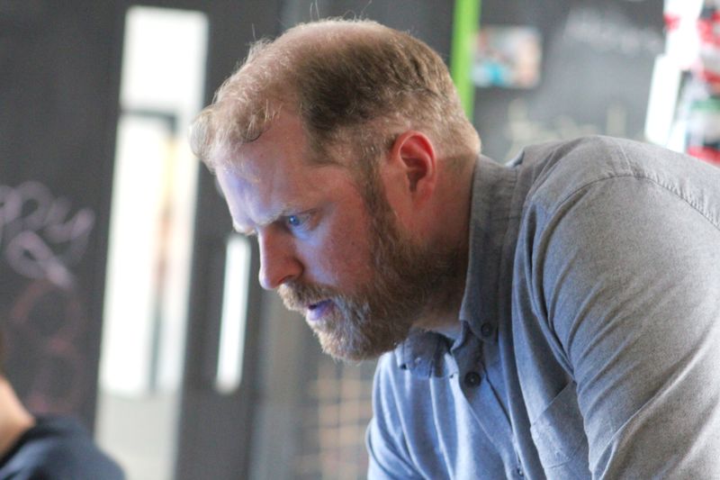 Martin Naughton leaning over a work area during Pizza and Programming at Farset Labs.