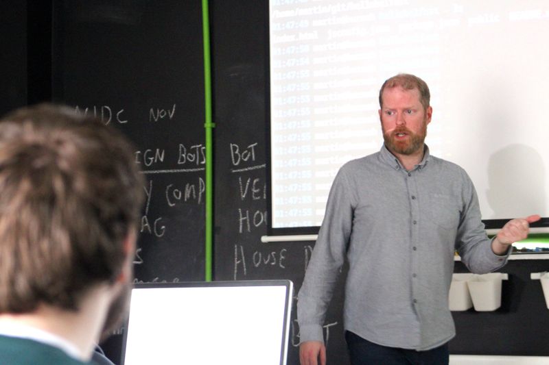 Martin Naughton presenting to students beside a projection screen at Farset Labs.