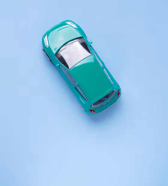 Top view of a green toy car on a light blue background.