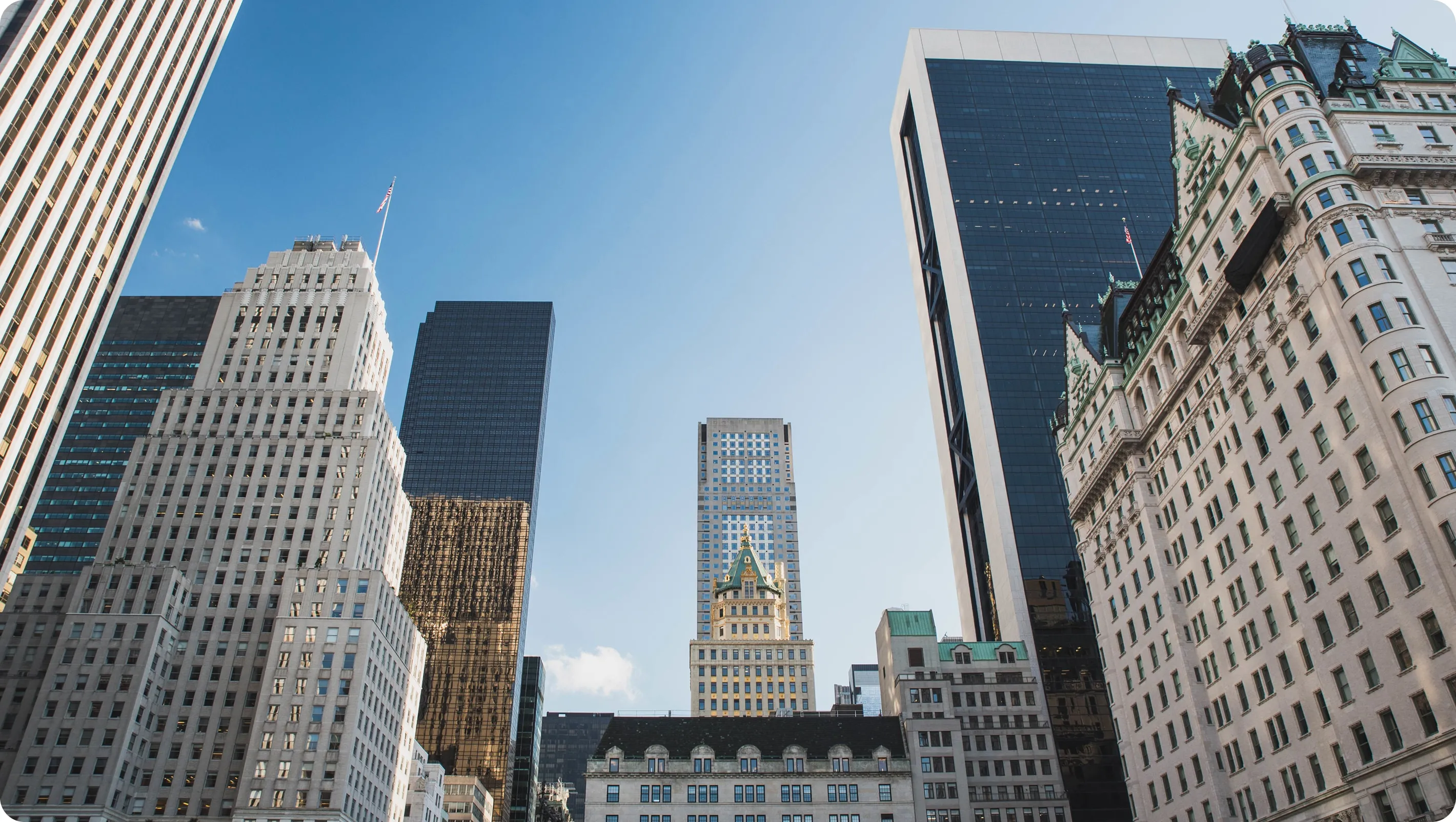 View of tall skyscrapers and historic buildings under a clear blue sky in a cityscape.