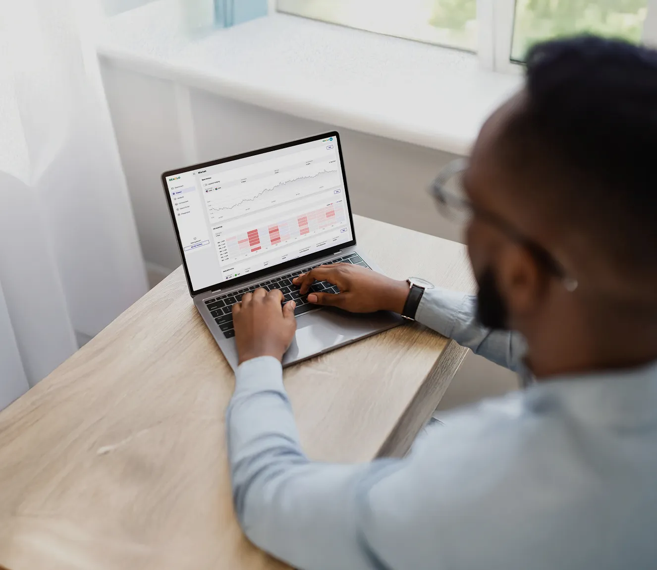 Person using a laptop showing stock market graphs and heatmap charts.