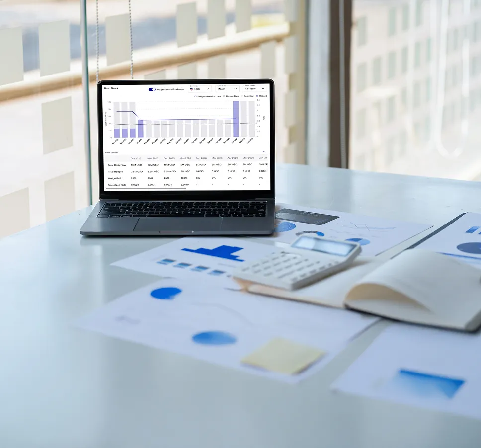 Laptop displaying a financial cash flow chart on a table with a calculator, documents, and an open notebook.