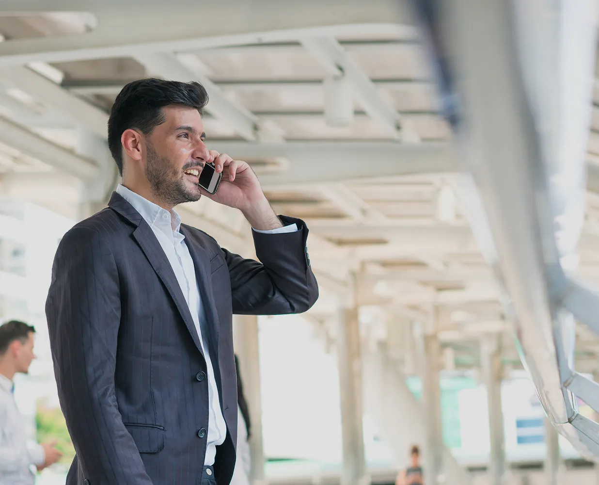 Smiling man in a suit talking on a smartphone in a modern indoor setting.