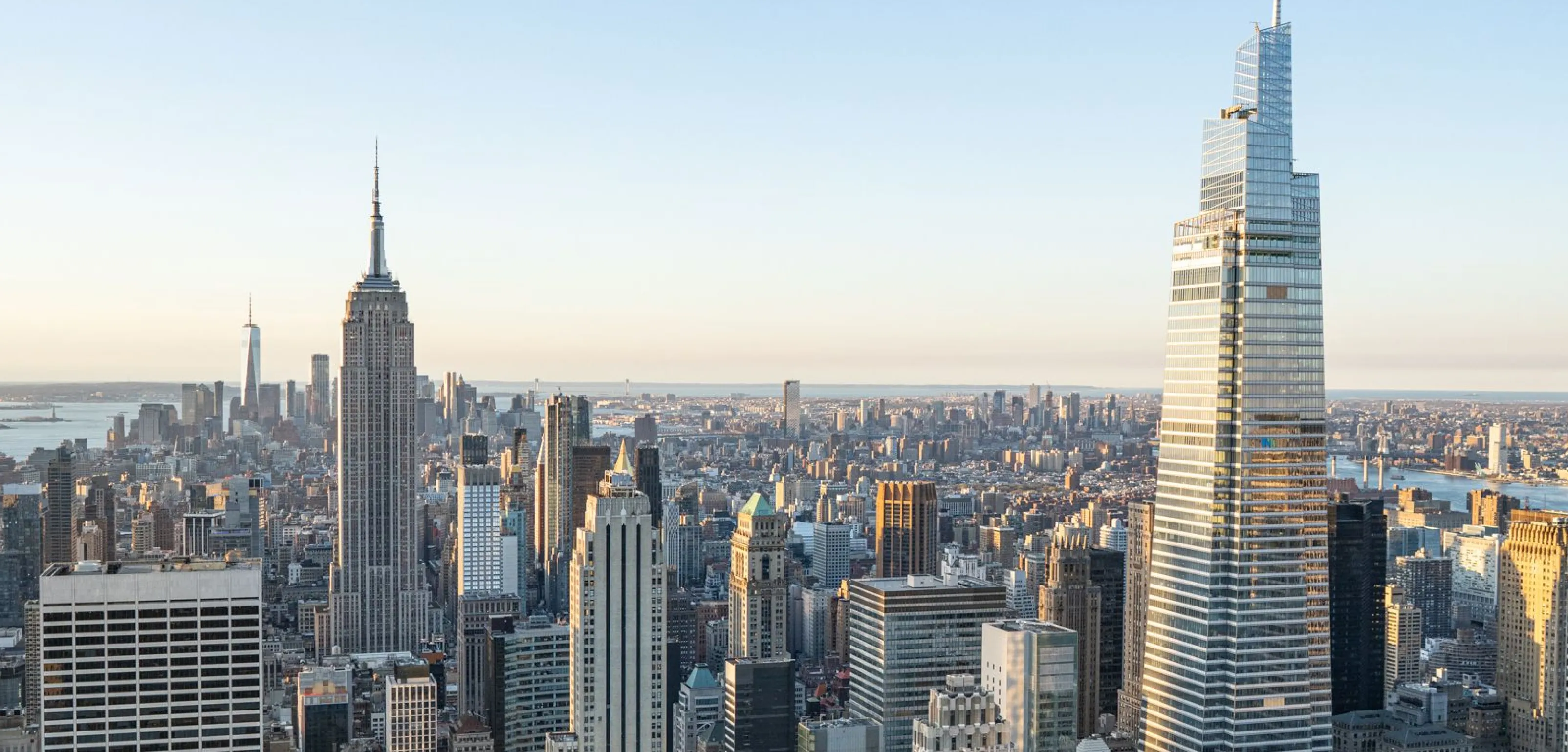 Panoramic view of New York City skyline featuring the Empire State Building and One Vanderbilt in daylight.