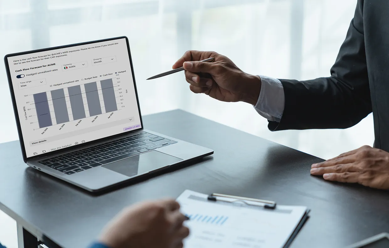 Person in a suit pointing at a laptop screen displaying a cash flow forecast chart during a business meeting.