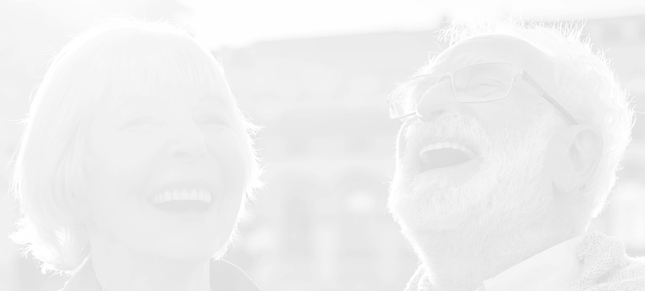 Senior man and woman with white hair laughing joyfully outdoors.