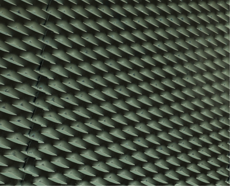 Close-up of a greenish textured surface with a pattern of overlapping, pointed, triangular shapes.