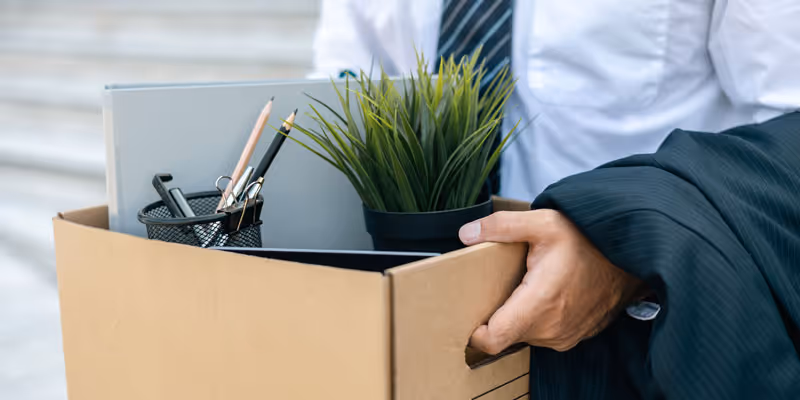 Person mit Karton und Bürounterlagen