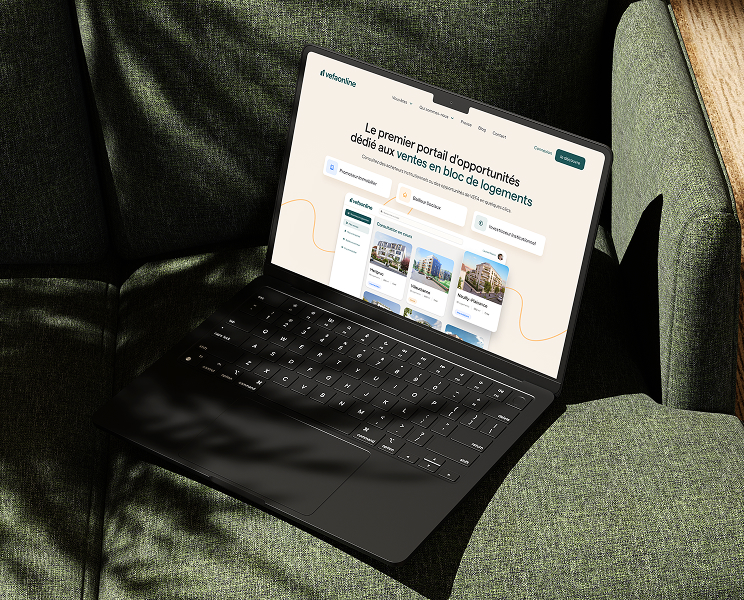 Ordinateur portable noir sur un canapé en tissu vert affichant une page web d'un portail de vente immobilière français.