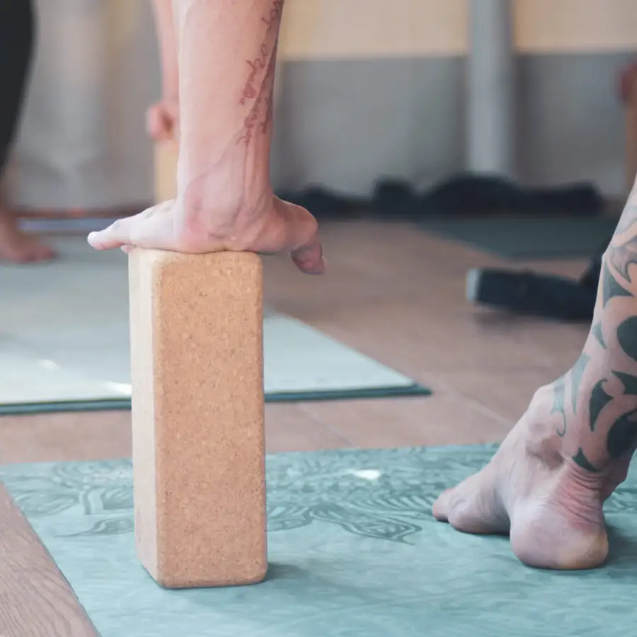 Close-up of a yoga student using a cork block for support during a hand balance pose at Floripa Yoga Retreat in Sicily, highlighting alignment-based practice