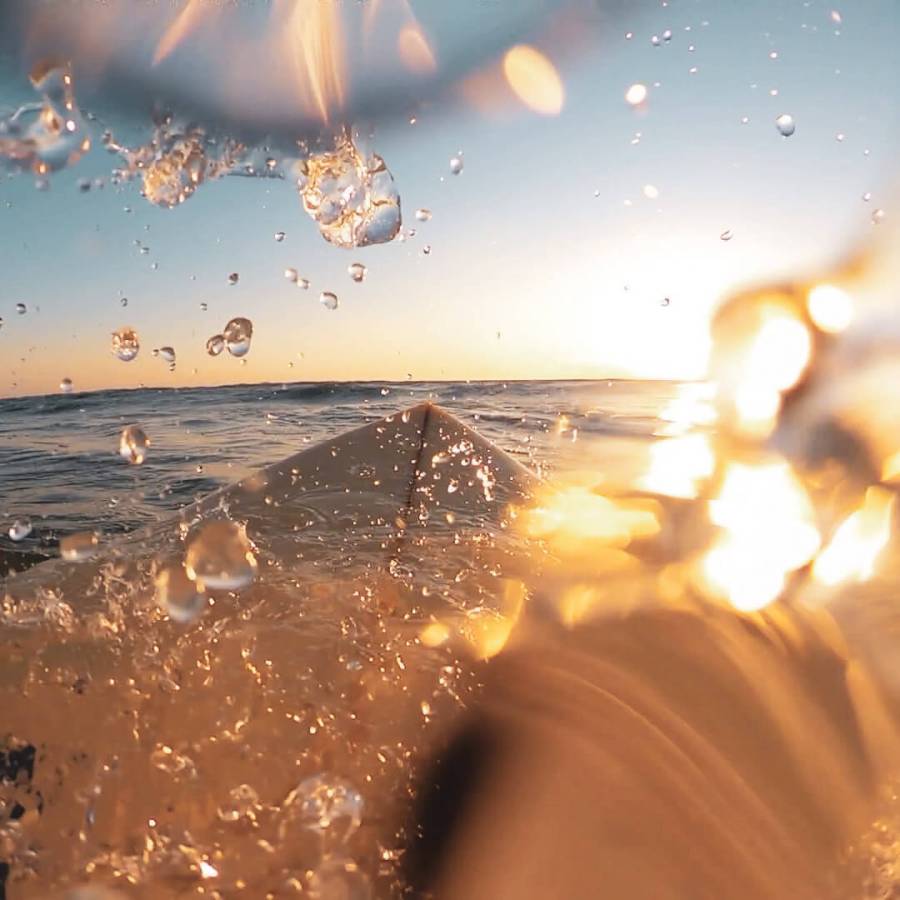 Immersive view from the water of a sunrise surf session near Floripa Surf and Yoga Retreat in Sicily, with waves, light, and motion
