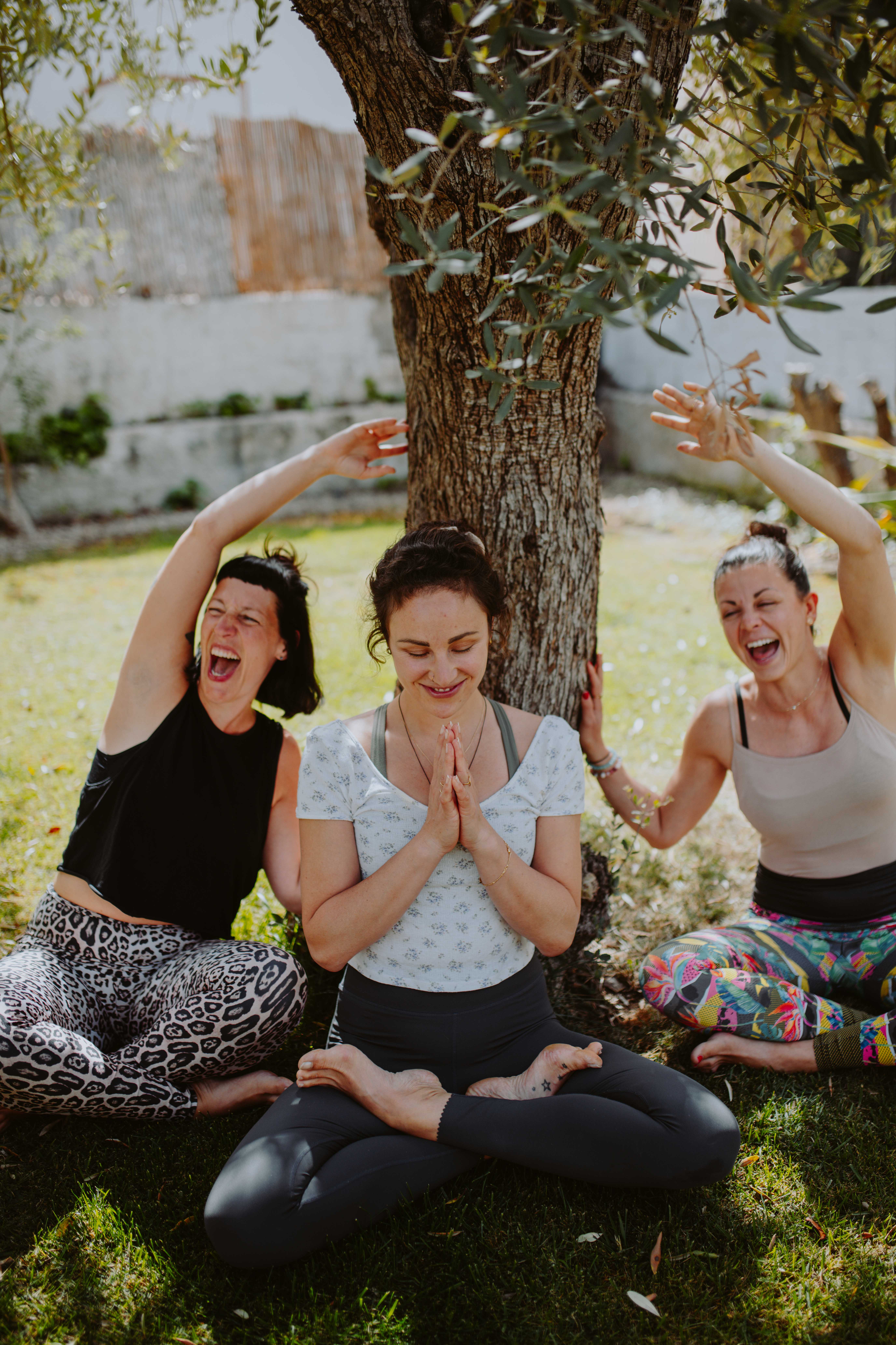 Joyful yoga practice under an olive tree at Floripa Surf and Yoga House in Sicily, a relaxing retreat for connection and wellbeing
