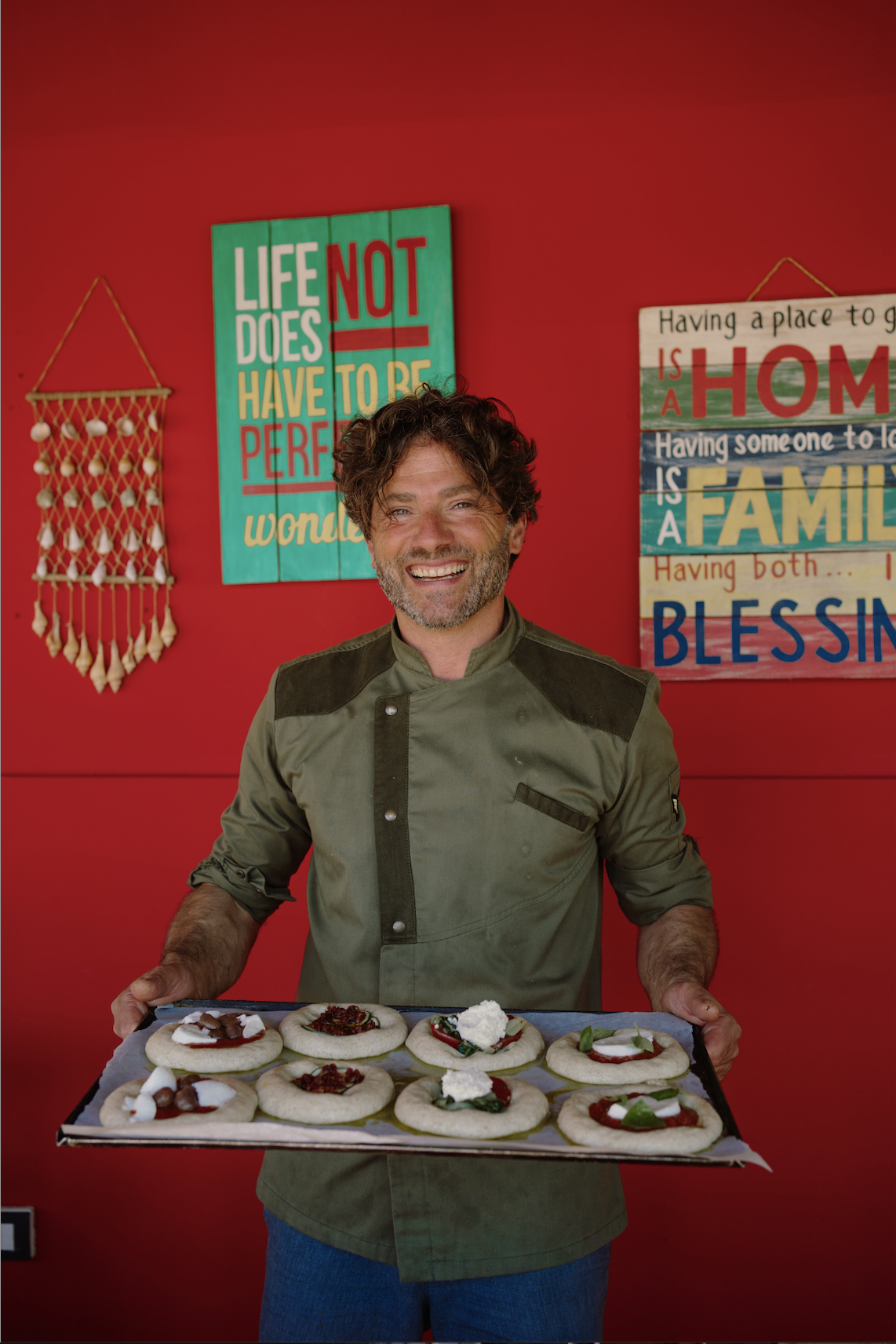 Chef Francesco at Floripa Surf and Yoga Retreat in Sicily holding a tray of fresh vegetarian Italian dishes, showcasing the retreat’s in-house gourmet cuisine