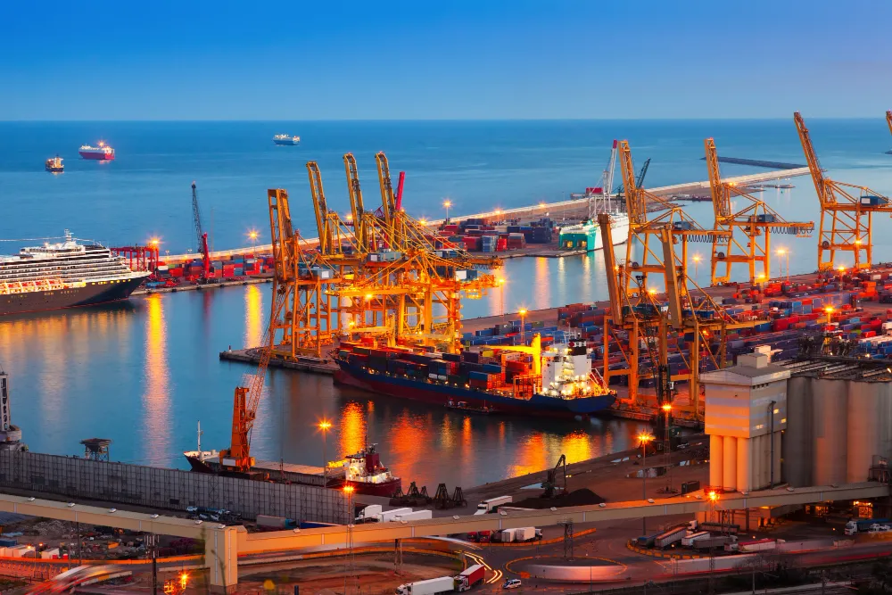 Containerhafen mit Kränen und Containerschiffen in der Abenddämmerung