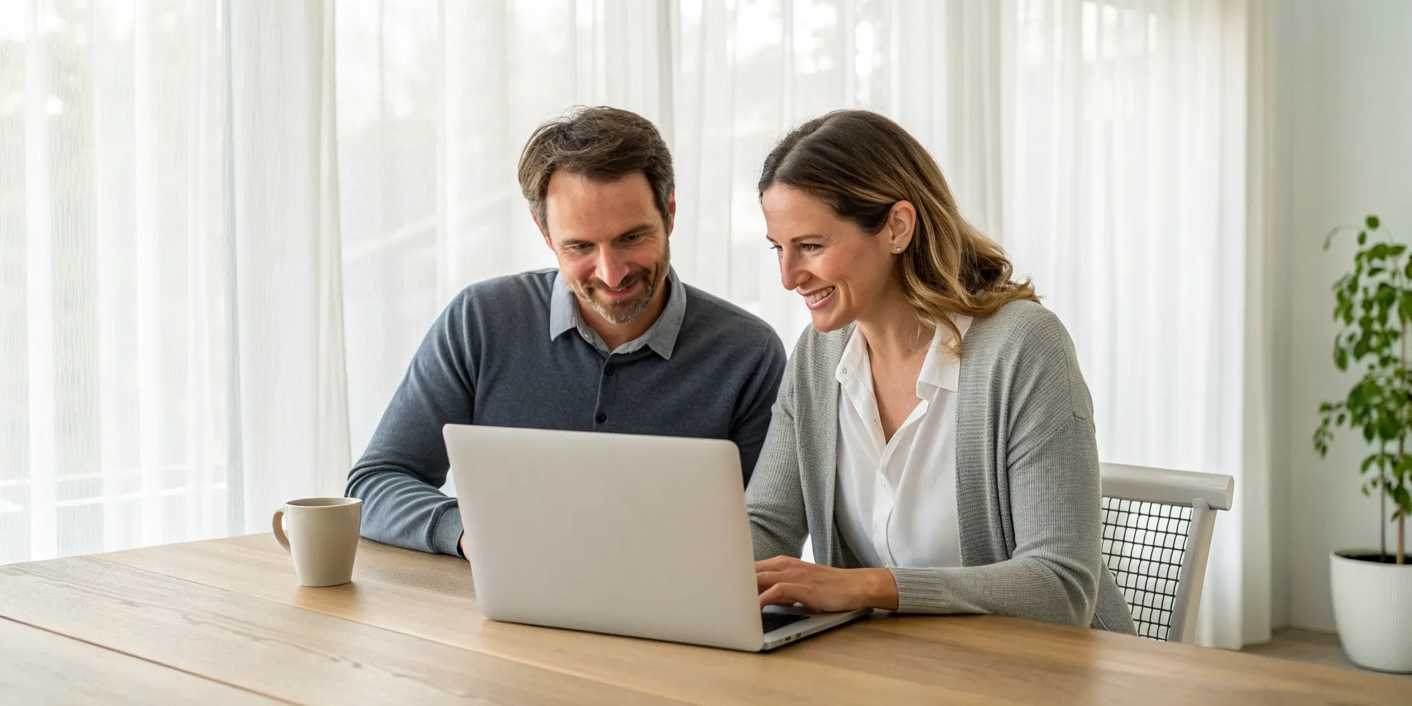 Couple smiling as they sign up for online relationship counseling on a laptop.