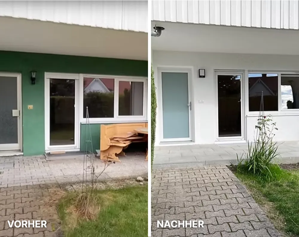 Moderne helle Küche mit weißen Schränken, Holzarbeitsplatte, Kochfeld und großer Fensterfront mit Blick auf Nachbarhäuser.