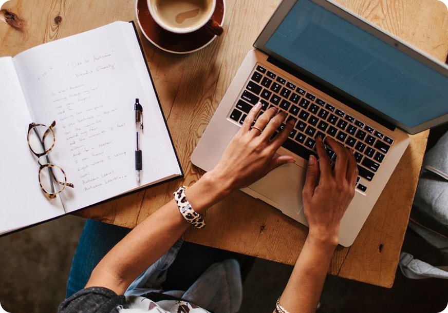 A graduation cap with a red tassel sits atop stacked coins in front of a glass jar filled with more coins, all arranged on what appears to be educational materials. The background shows a blue surface with chalk-drawn education-related icons including clocks and graphs, symbolizing the financial planning and savings needed for education.