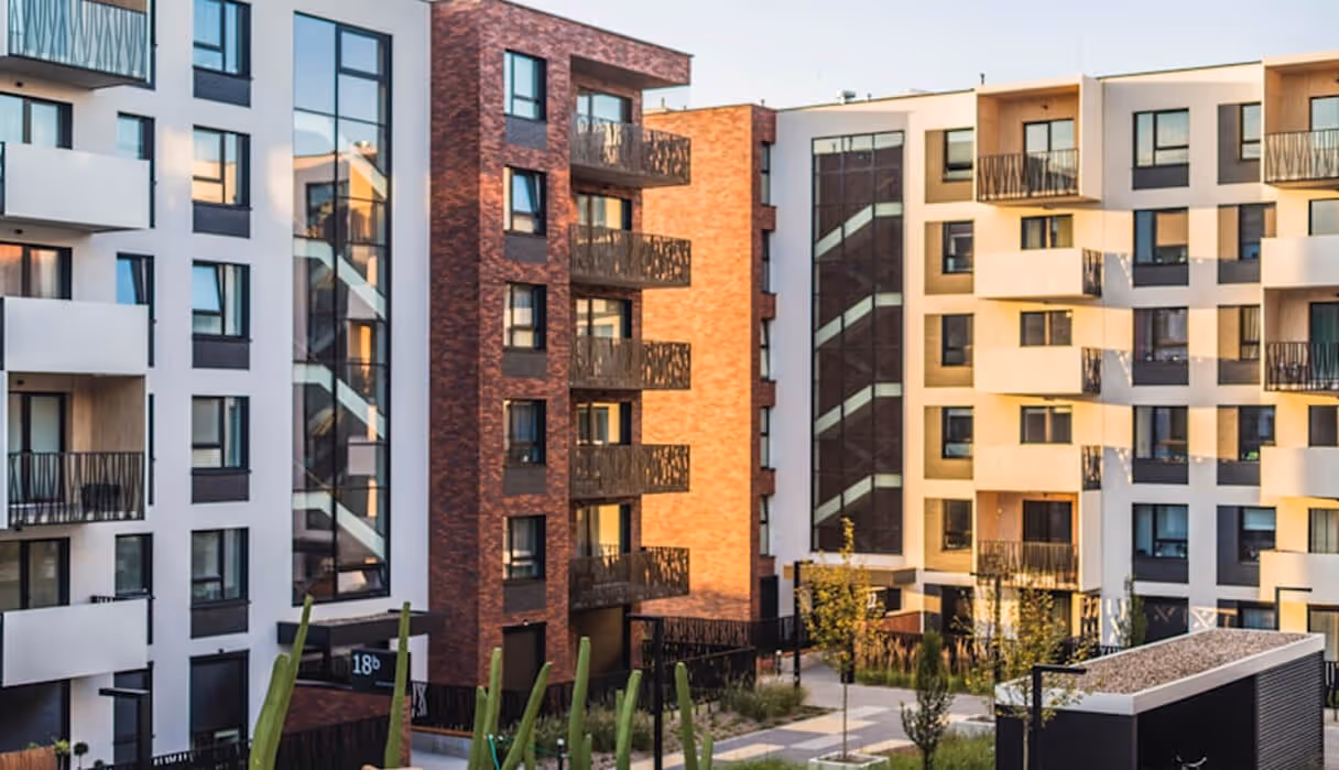 Modern multi-story apartment buildings with balconies and landscaped courtyard in the foreground.