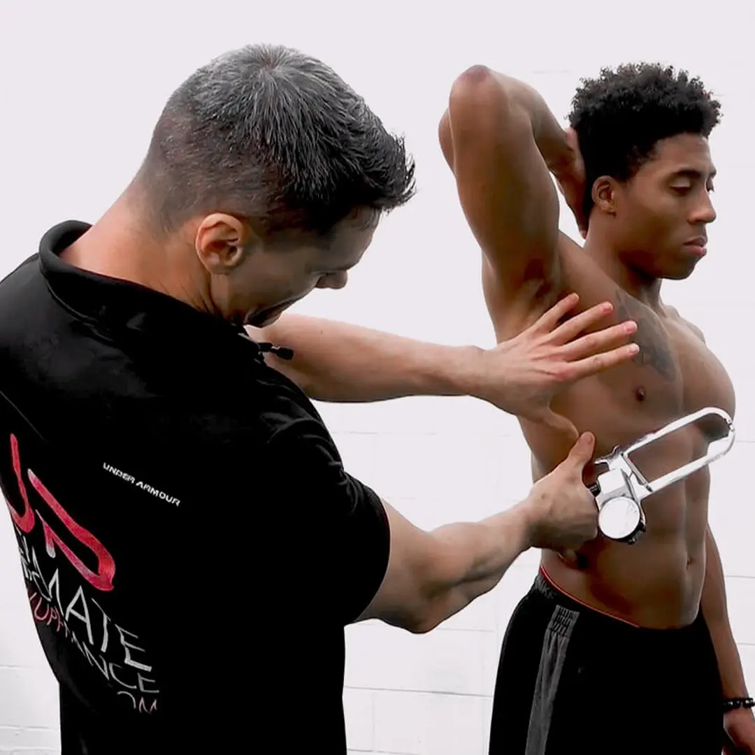 Fitness professional using a body fat caliper to measure skinfold thickness on a shirtless man’s side.