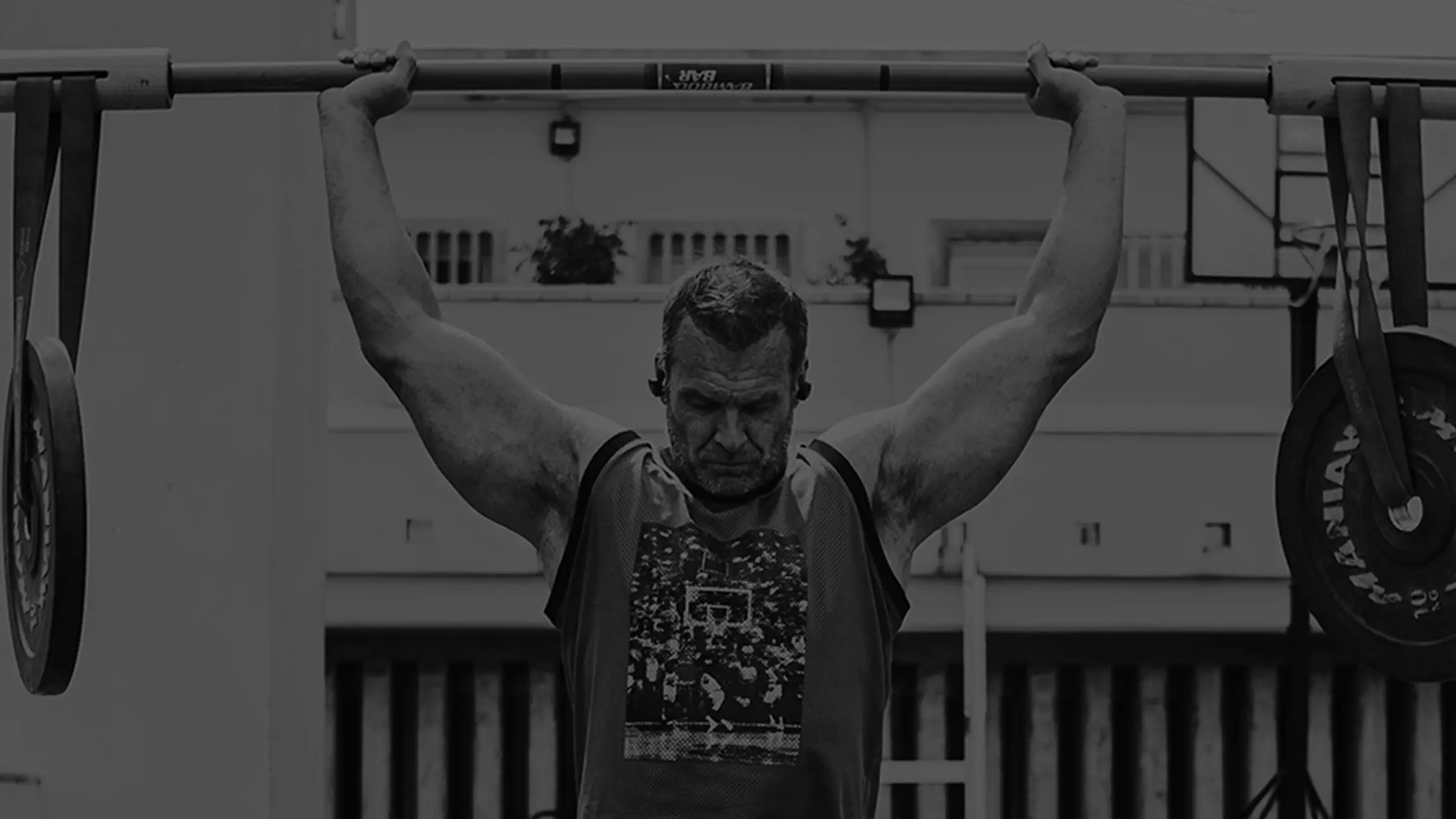 Man lifting a barbell overhead with weighted plates attached.